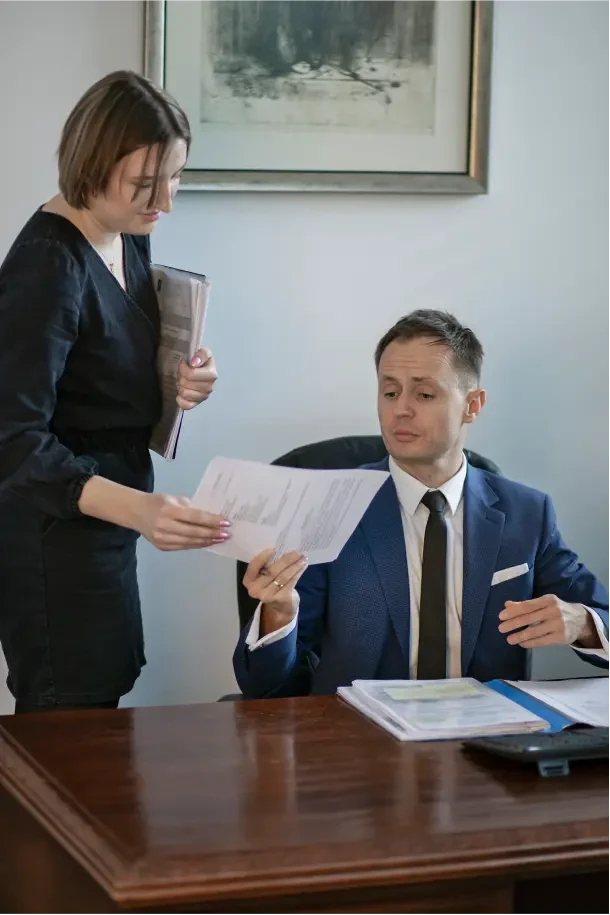 Piotr Nowakowski ubrany w garnitur przekazujący dokument