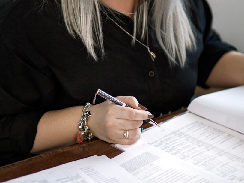 Kobieta w czarnym ubraniu podpisująca dokument