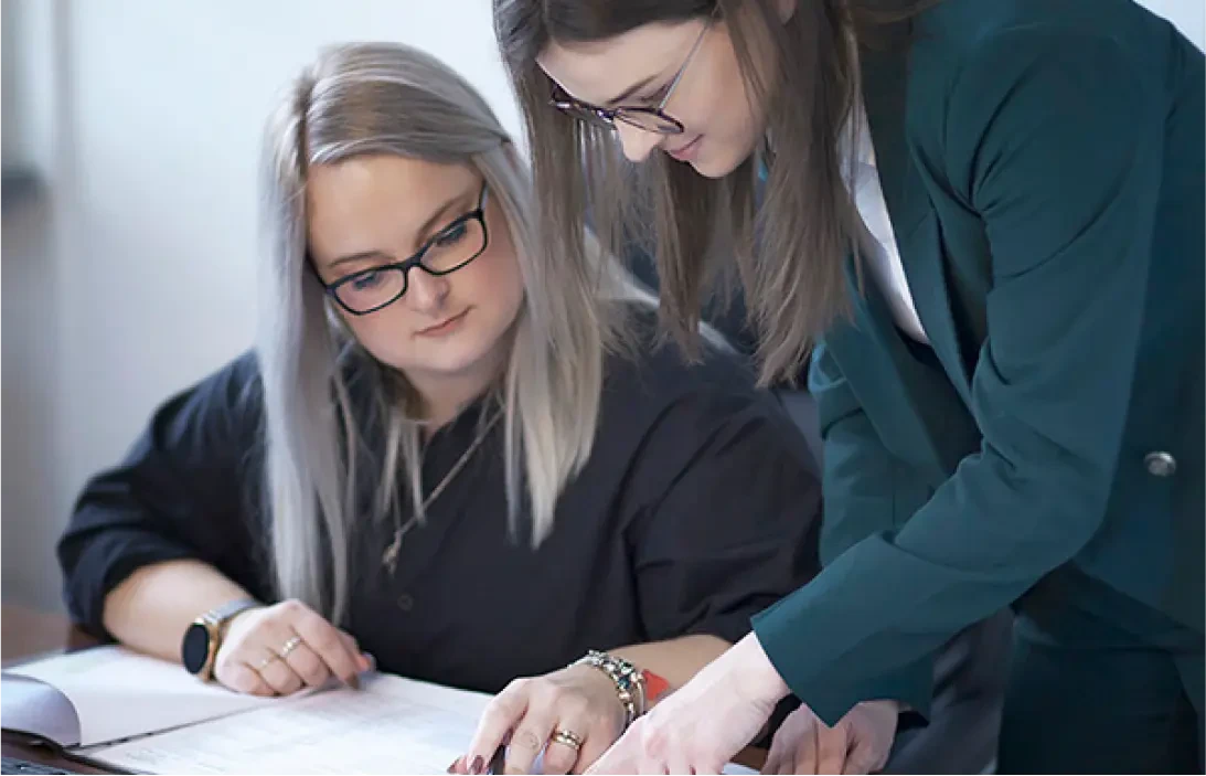 Dominika Sujka-Kujawiak rozmawiająca z osobą i omawiająca dokumenty.